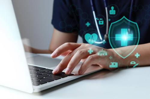 closeup of healthcare professional typing on laptop with graphic symbols cybersecurity in healthcare mobile medical corporation cybersecurity month october 2025