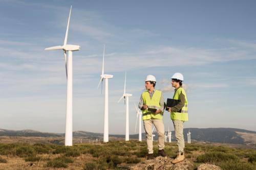 Two construction workers standing in a large open field with windmills in the background rural healthcare services mobile medical corporation 